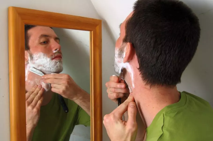 мужчина бреется перед зеркалом