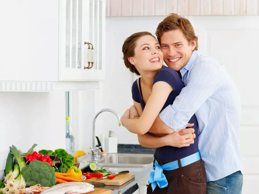 парень обнимает девушку на кухне